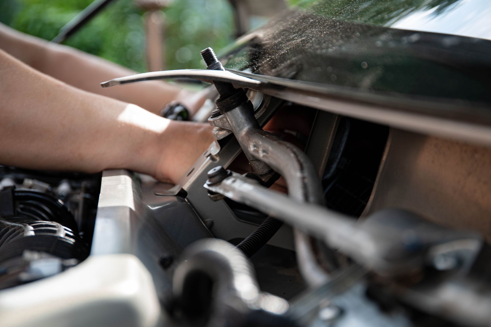 Close-up of a mechanic working on a car engine with tools in hand