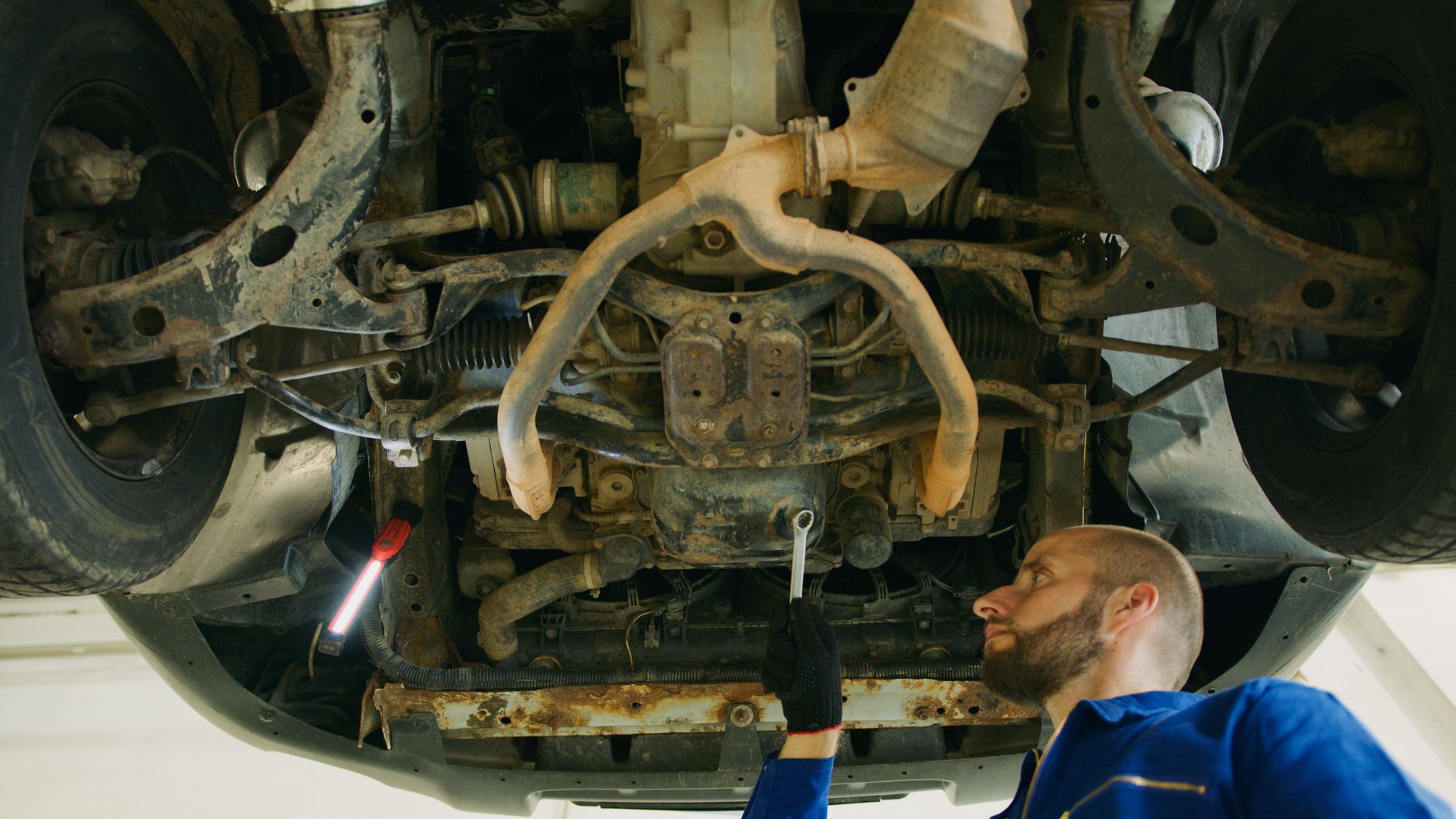 Mechanic examining a vehicle undercarriage in the garage