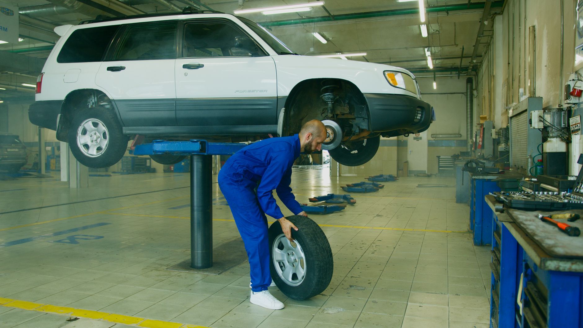 Mechanic replacing a tyre on a lifted SUV