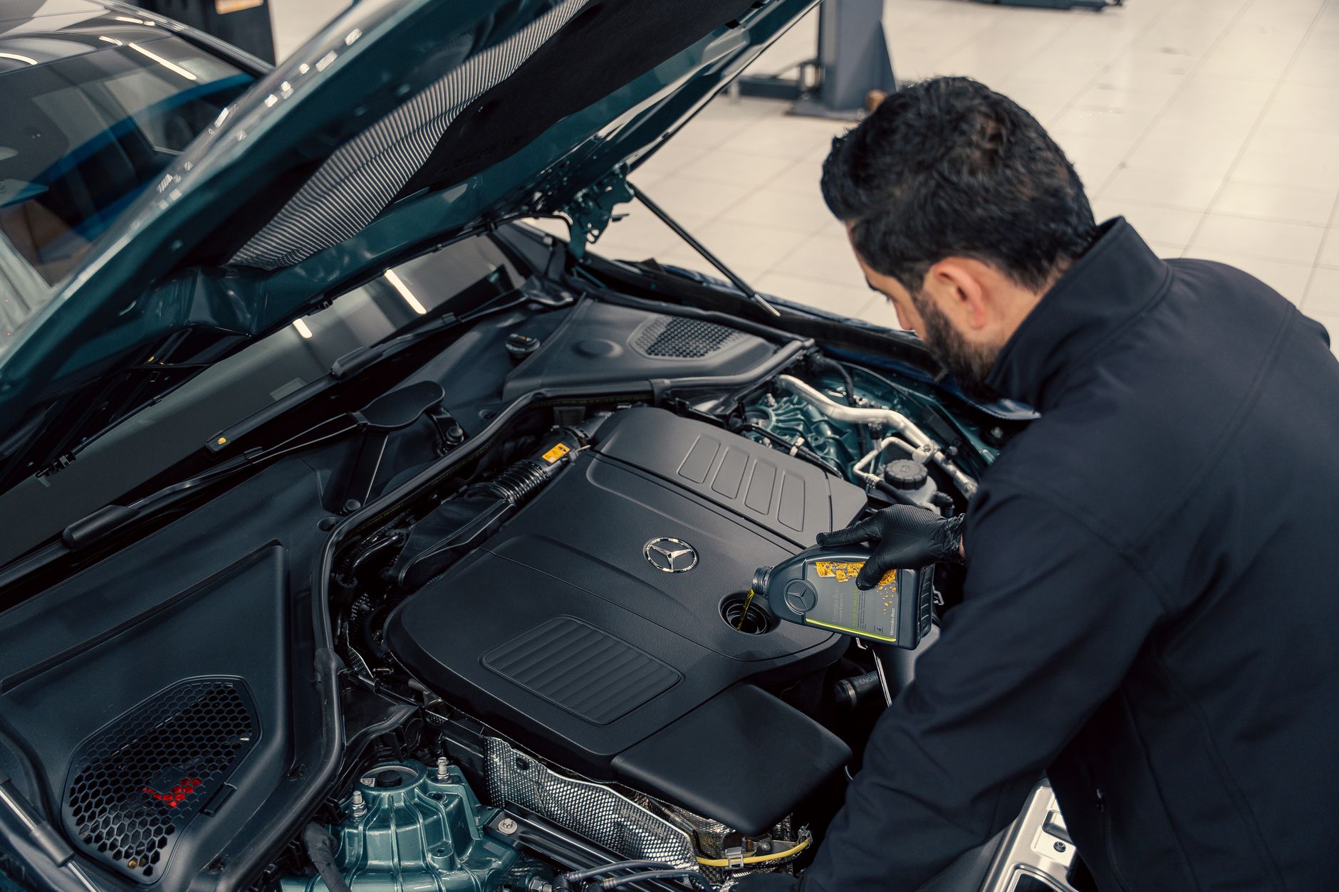 Mechanic filling engine oil in a car at a service centre