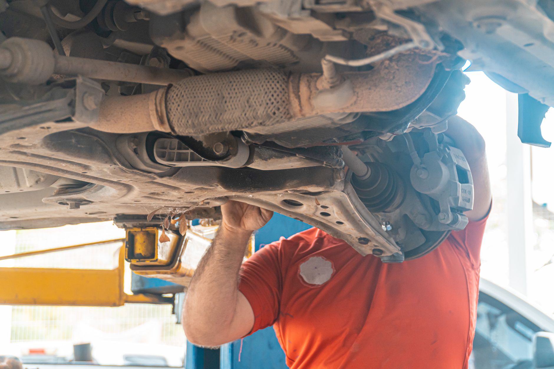 Mechanic inspecting the underside of a vehicle in a garage