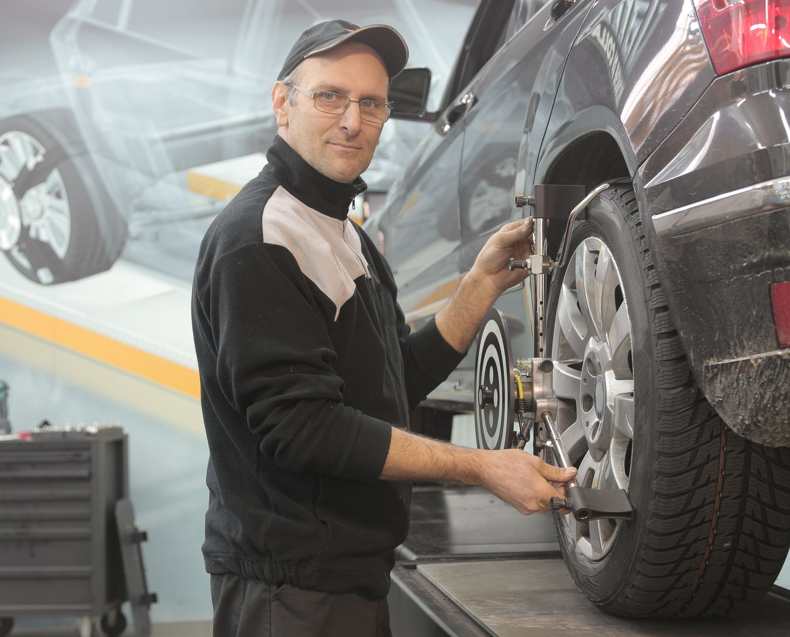 A mechanic performing a wheel alignment on a car