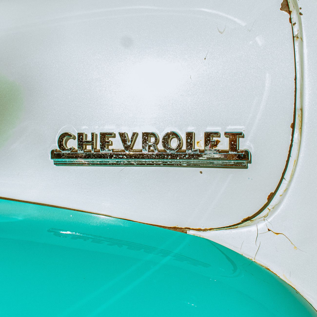A vintage car emblem with turquoise paint, close up