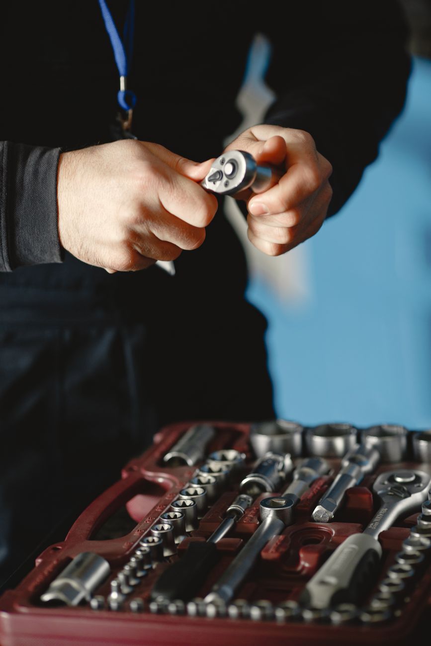 A mechanic holding a wrench over a toolbox in a workshop bay