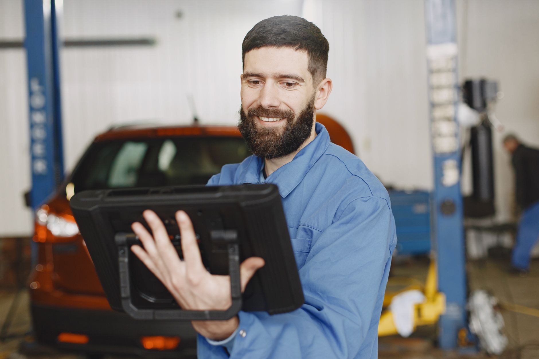 A smiling mechanic using a tablet for vehicle diagnostics
