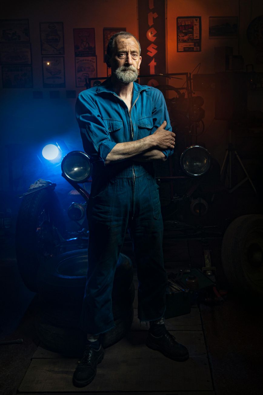Portrait of a bearded mechanic standing in a workshop with vintage tools
