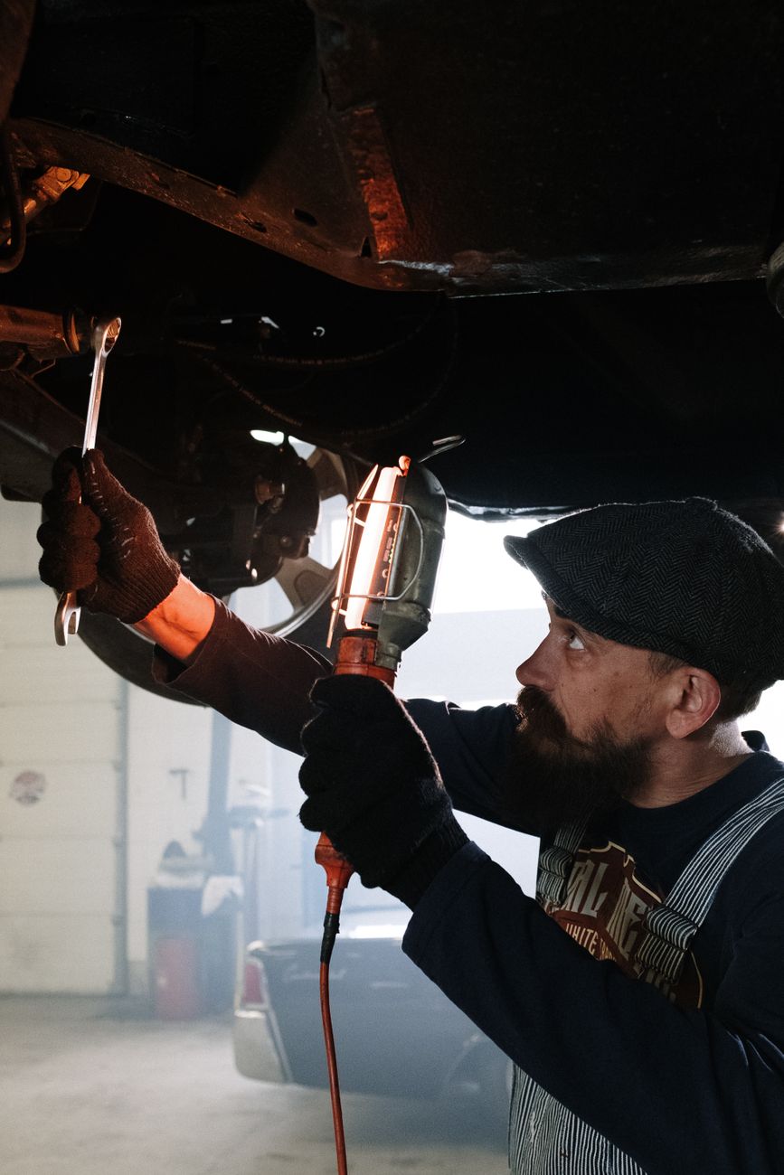 Portrait of a bearded mechanic working under a car