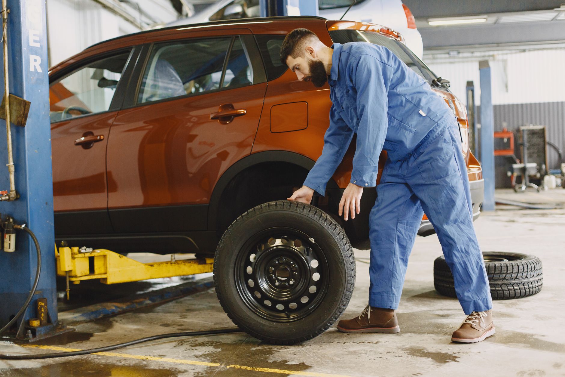 Photo of a mechanic replacing a tire on a red SUV
