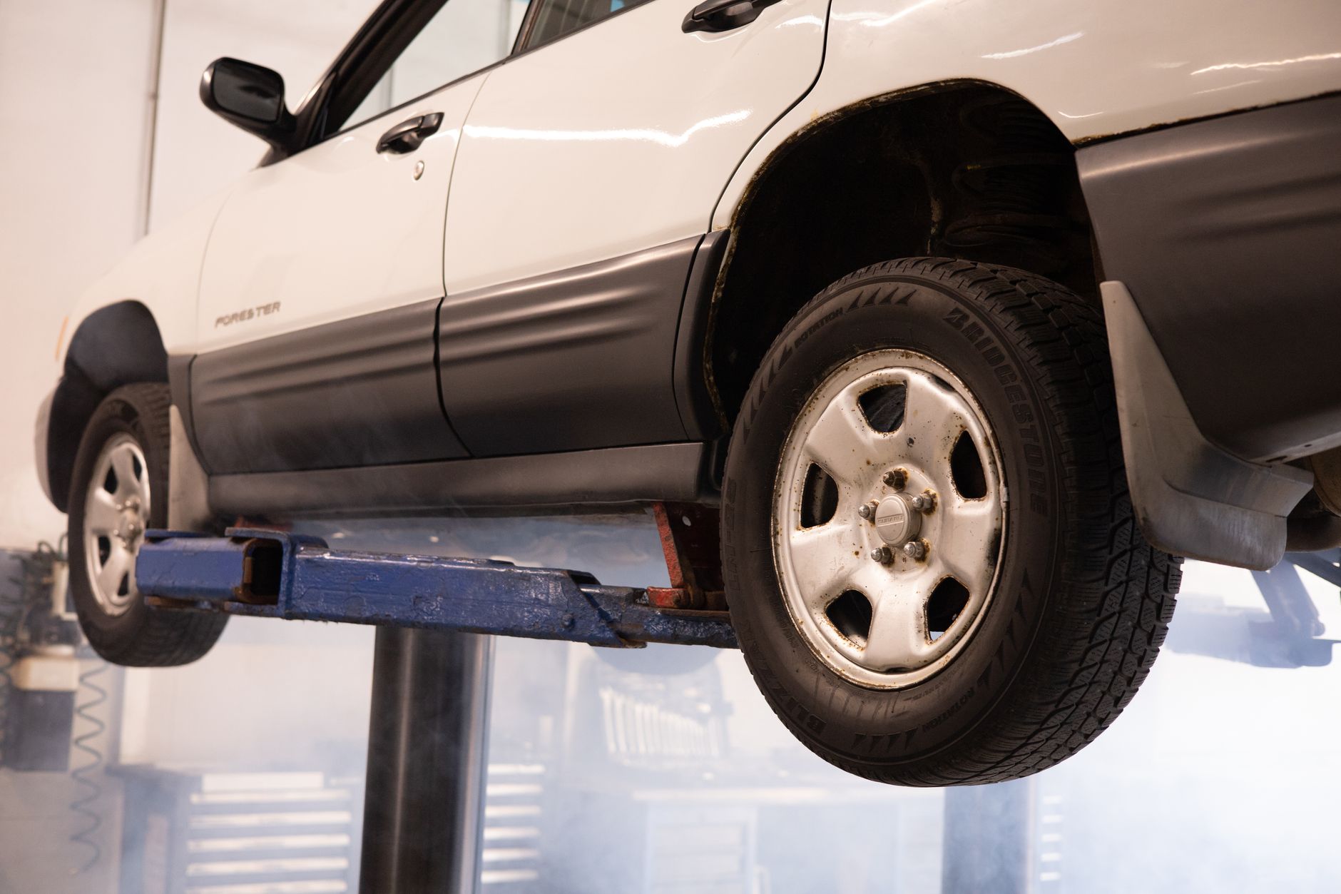 Photo of a white car raised on a lift in a repair shop