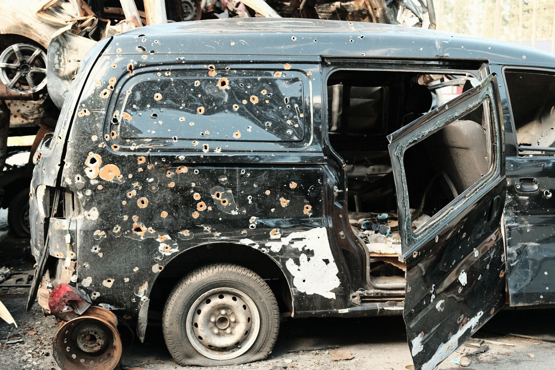 A damaged black van with a battered body in a yard