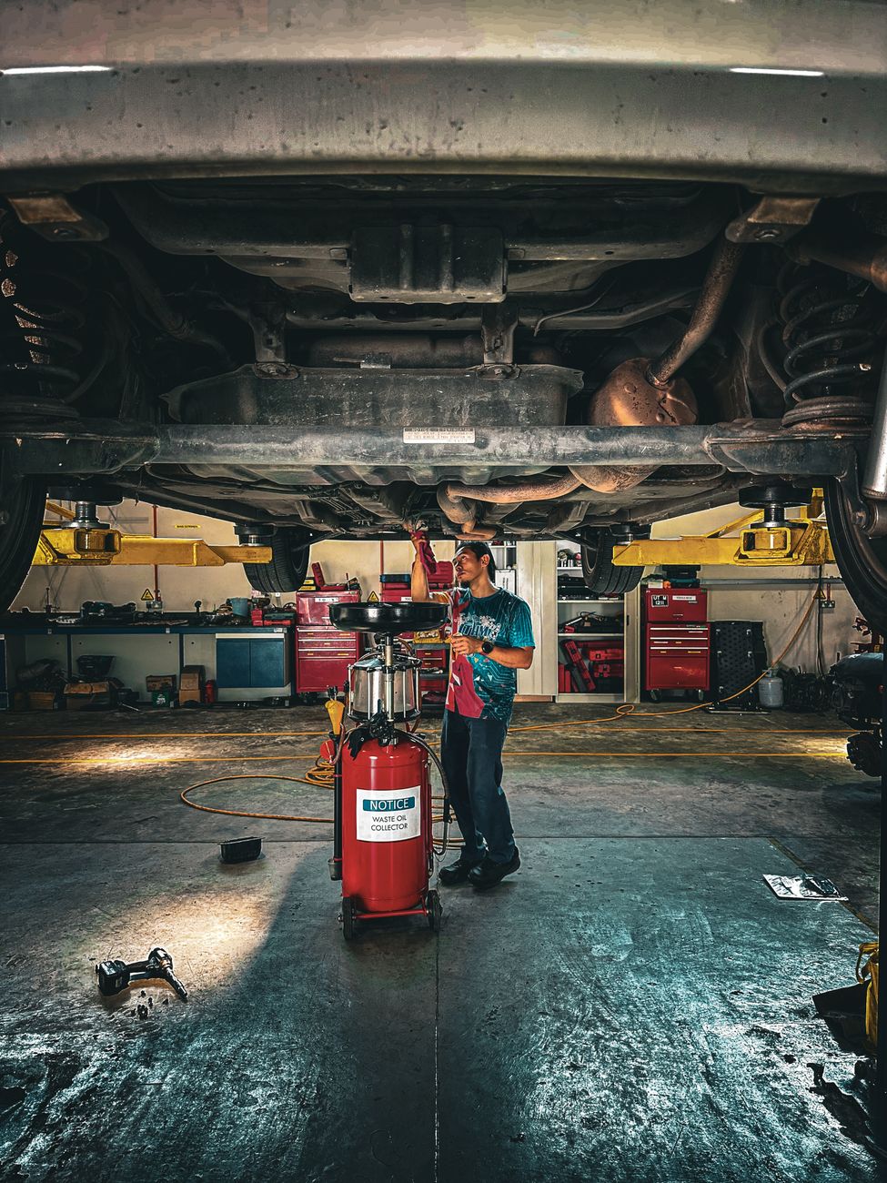 A mechanic inspecting the underside of a car in the garage