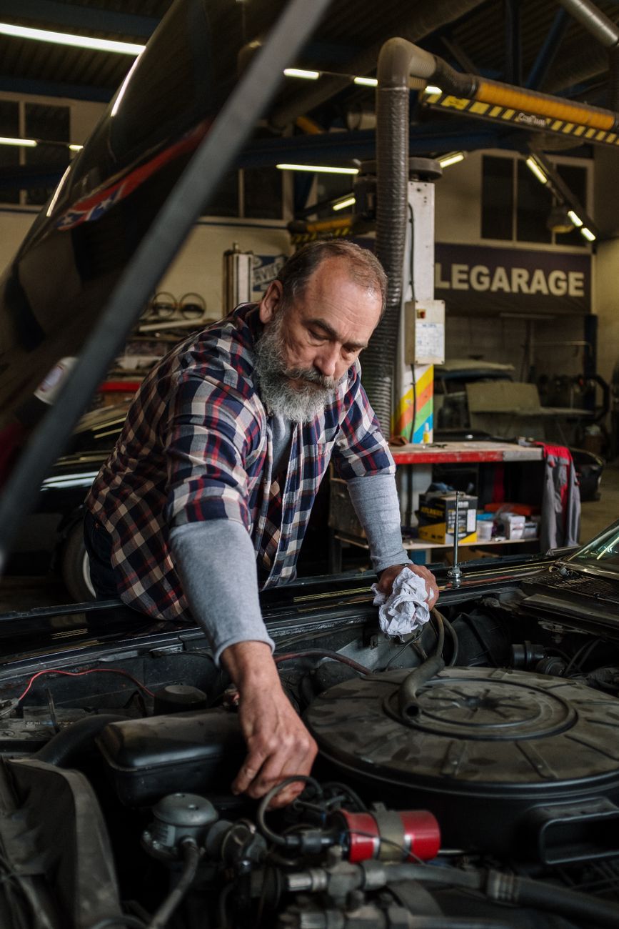A bearded mechanic repairing a car engine in the garage