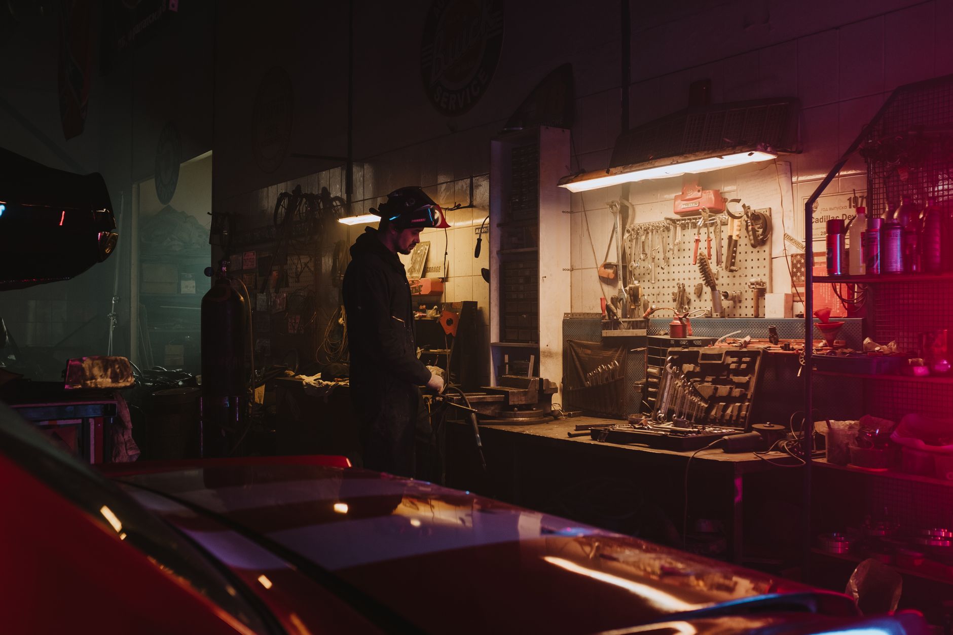 A mechanic working in a dimly lit garage surrounded by tools