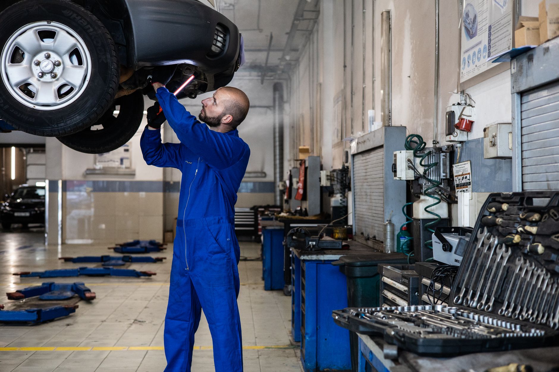 Mechanic inspecting a raised car in a workshop under lamp light