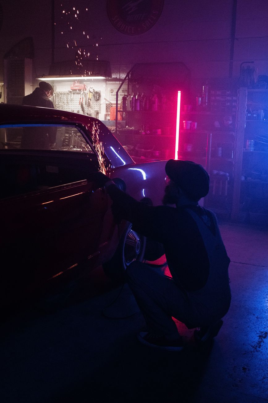 A mechanic sitting on a car in a workshop
