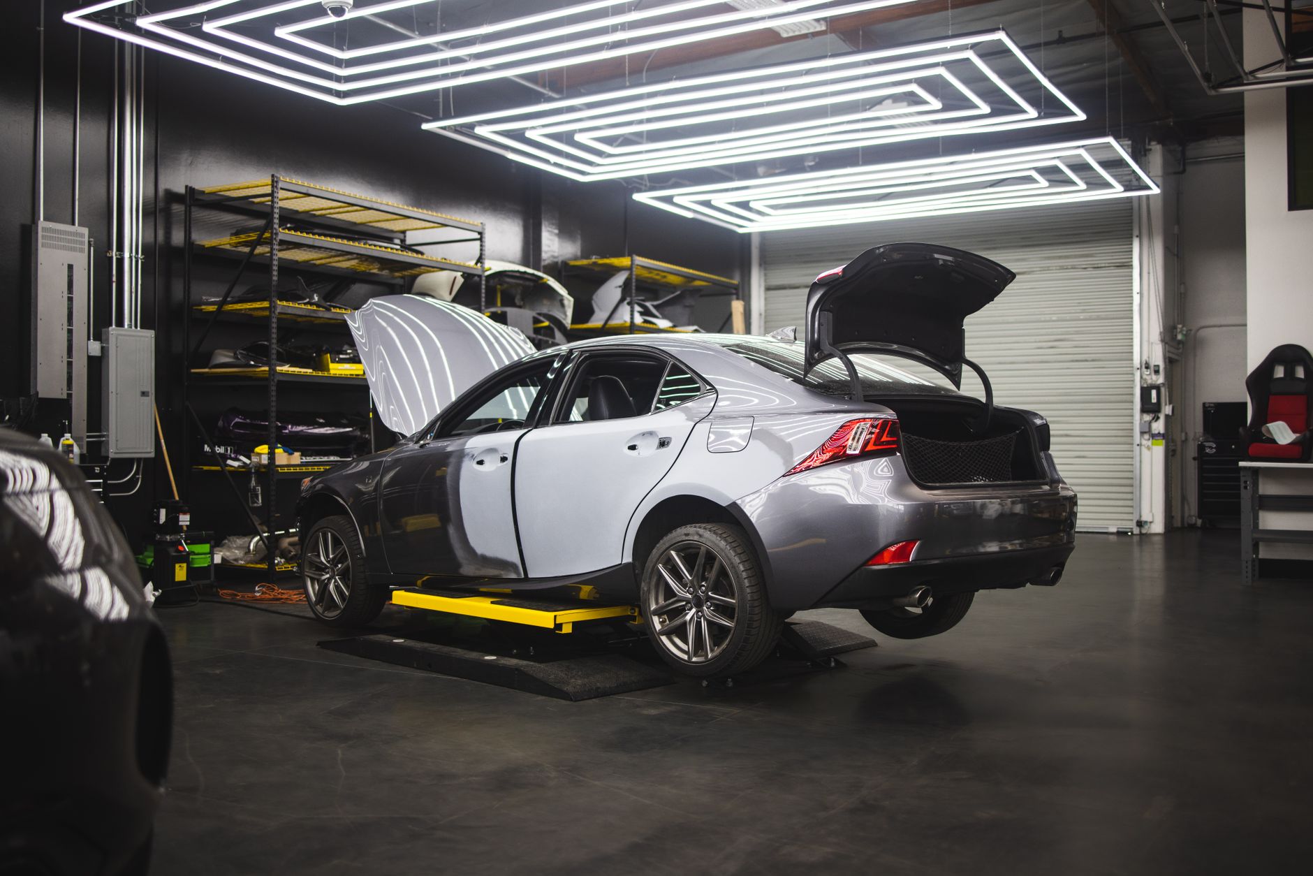 A grey car being repaired in a modern auto repair shop