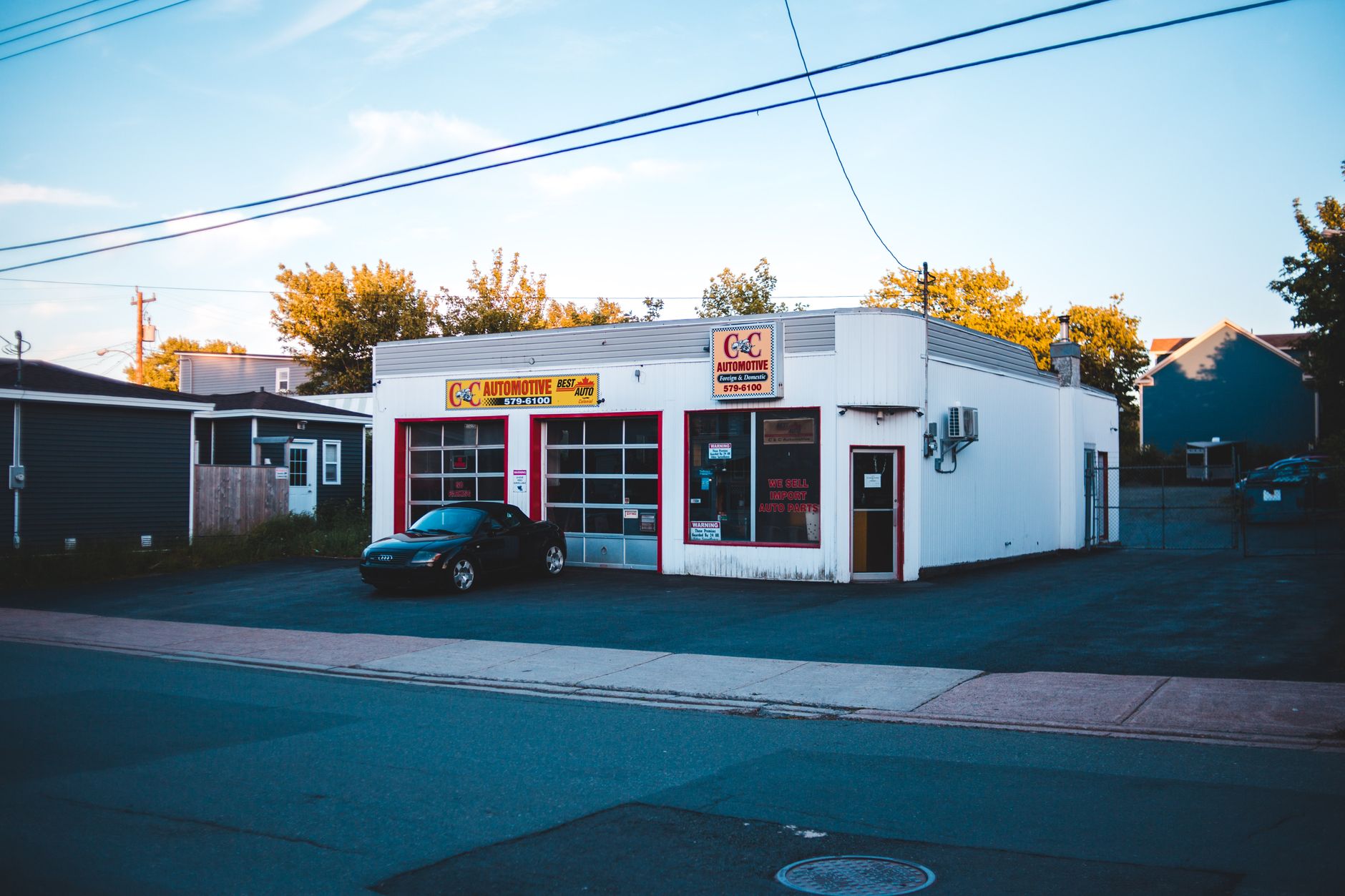 An automotive repair shop with a parked sports car at sunset