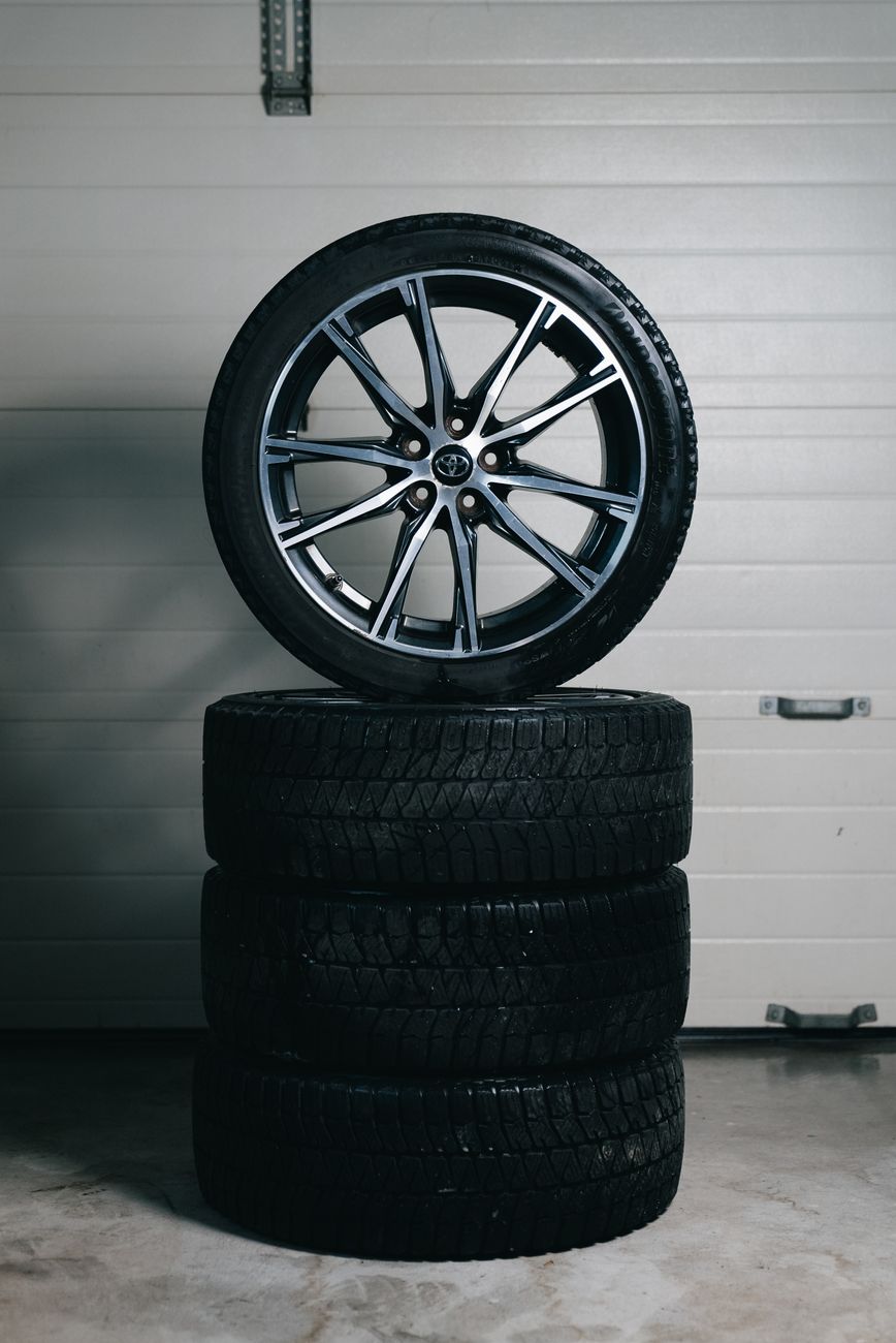 Stacked car tyres with an alloy wheel on top in a garage