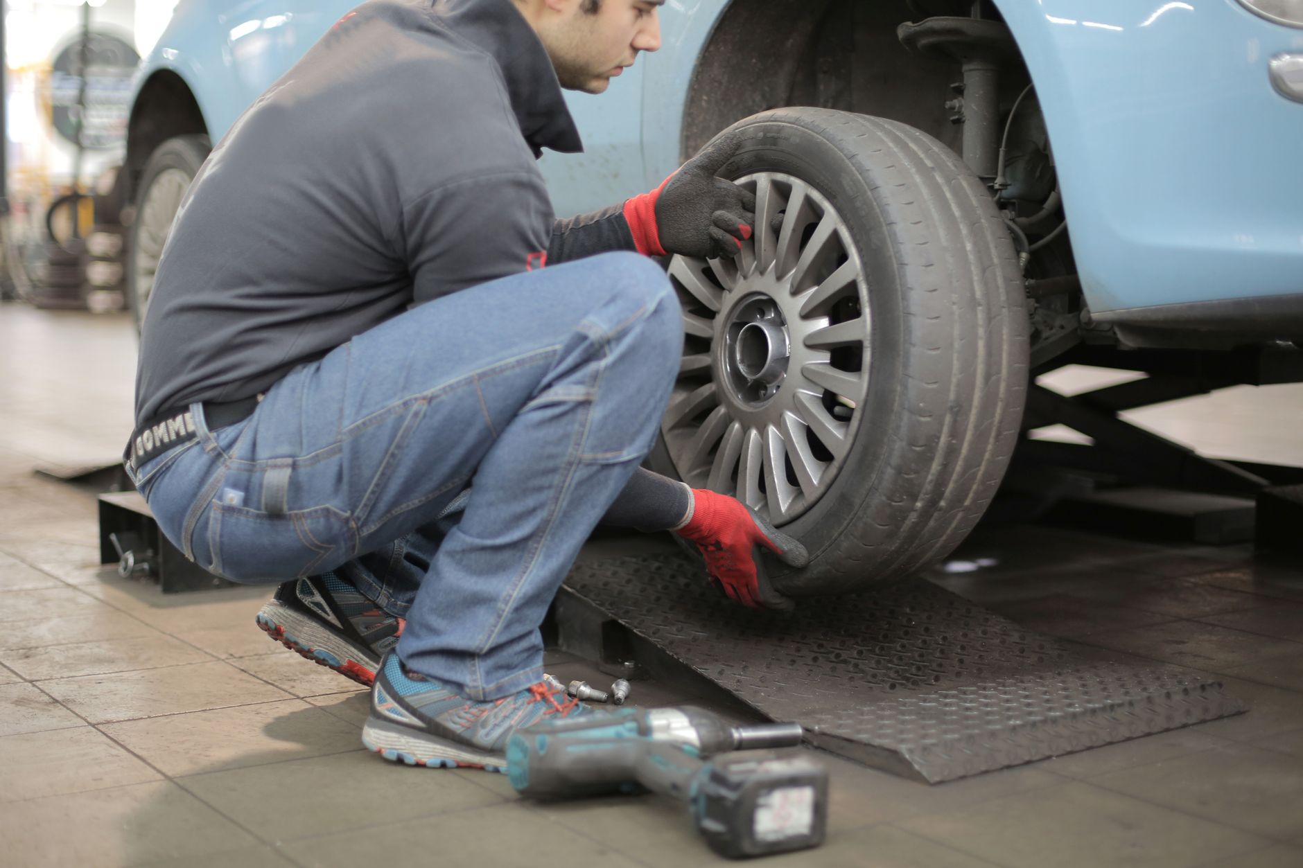 A mechanic changing a car tyre indoors with tools
