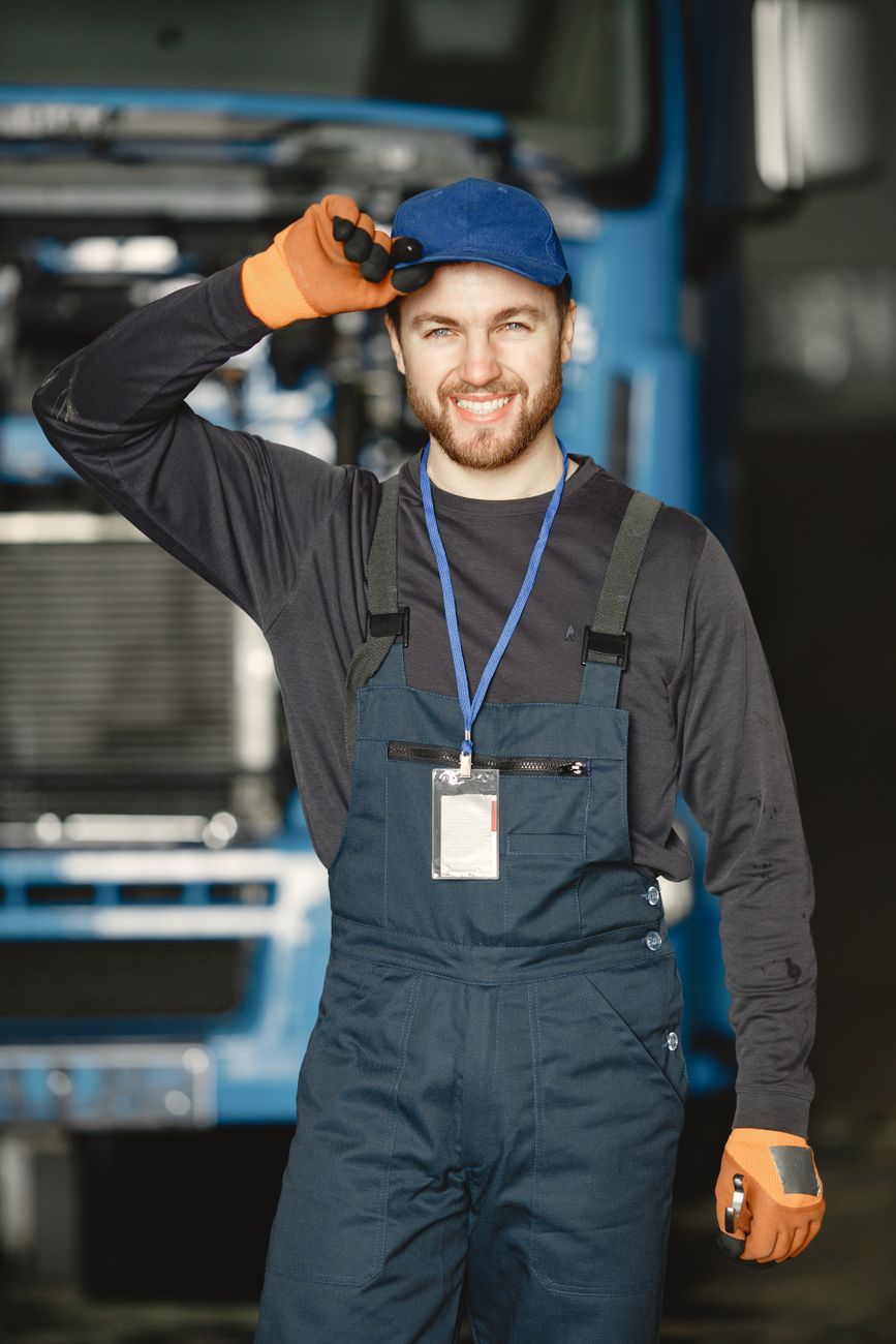 A mechanic in uniform standing at the workplace in front of a truck