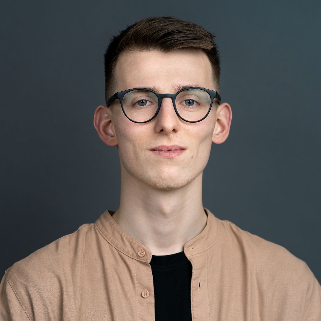 A young man wearing glasses and a button-down shirt