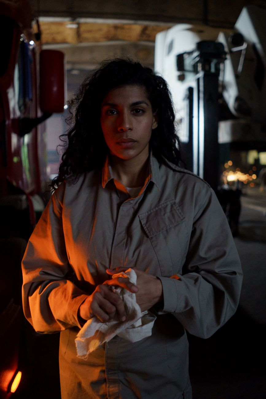 A woman auto mechanic holding a cloth in a garage