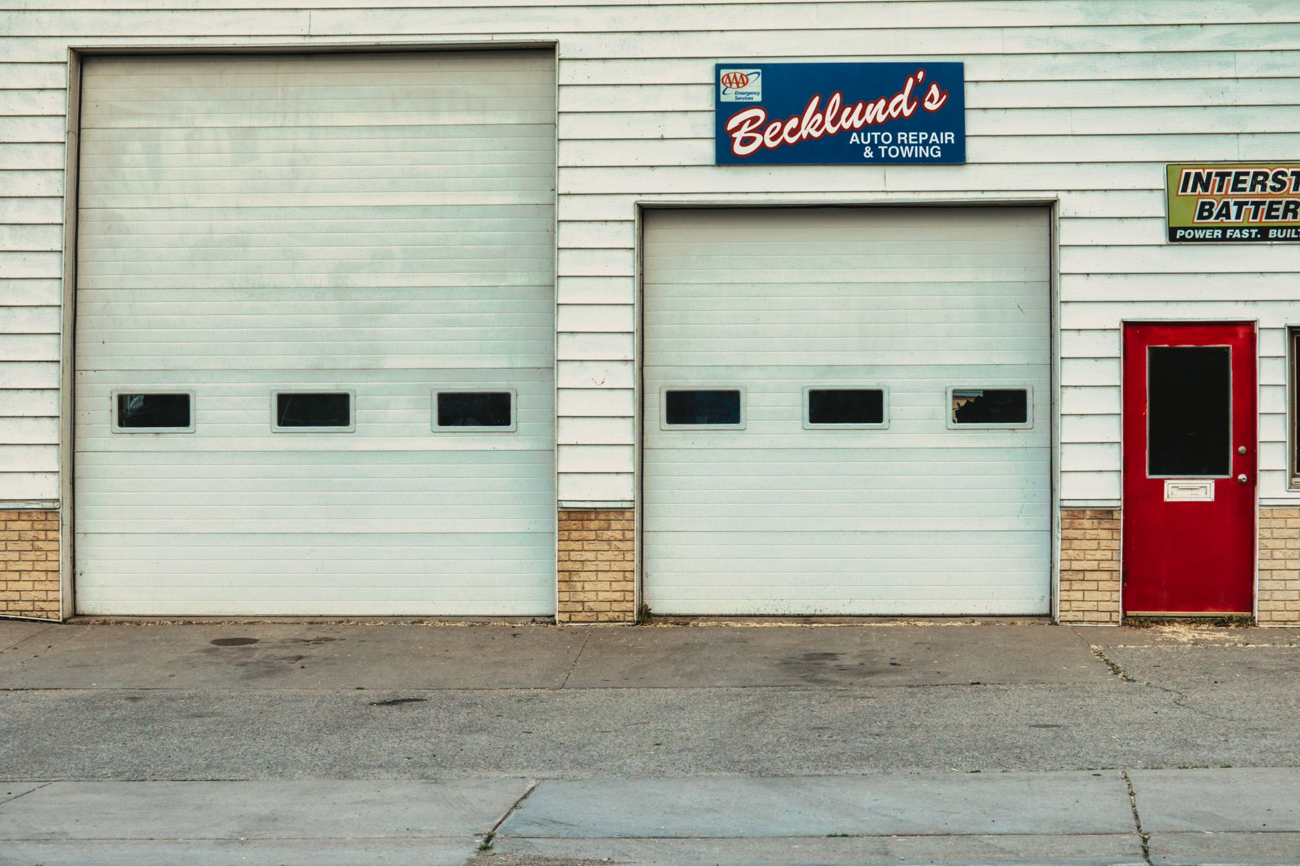 A repair shop front with roll-up doors and signage