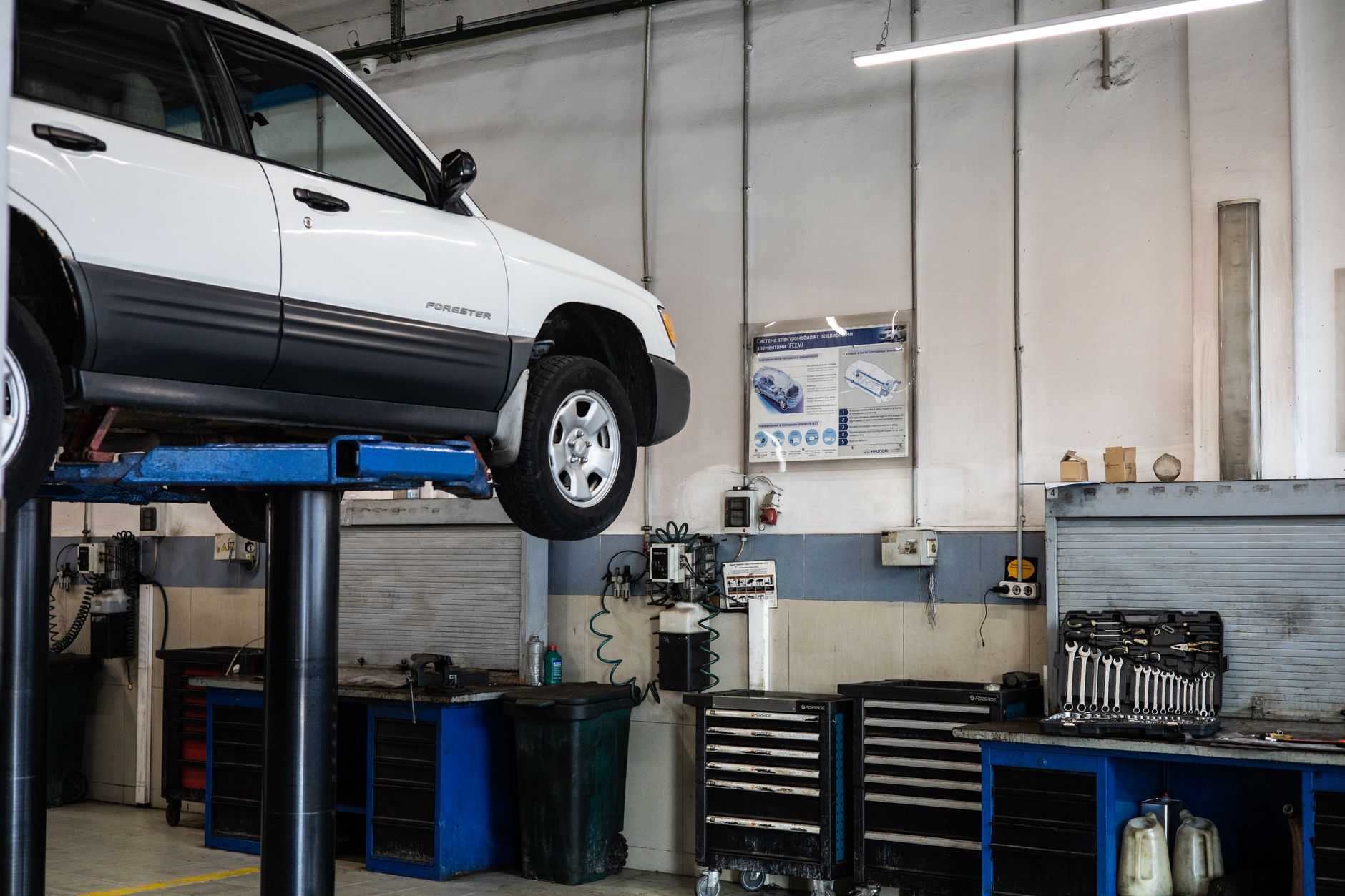 A car raised on a lift in an automotive repair shop with tools around it