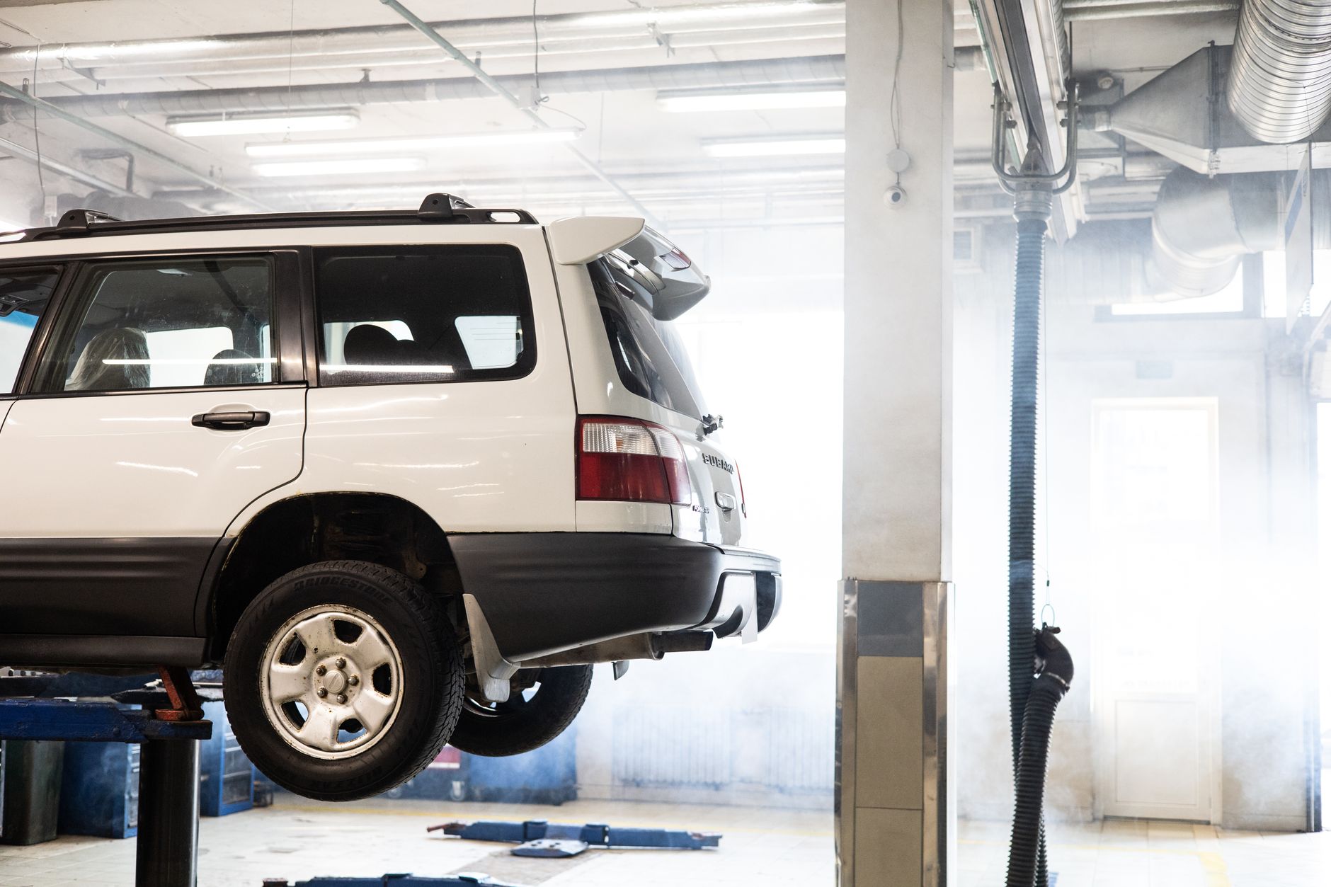 A white SUV raised on a lift inside an auto repair shop