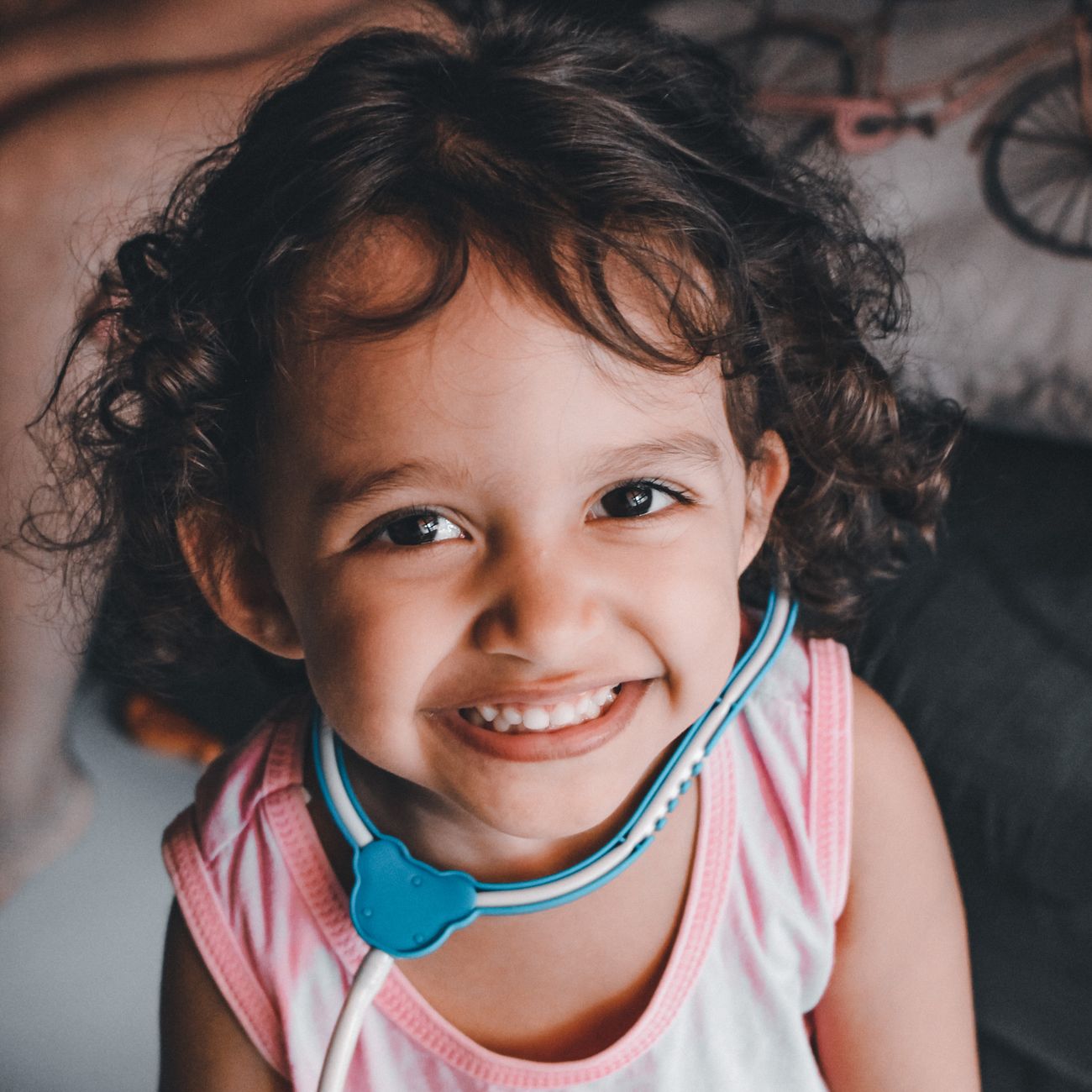 A smiling child playing with a toy stethoscope