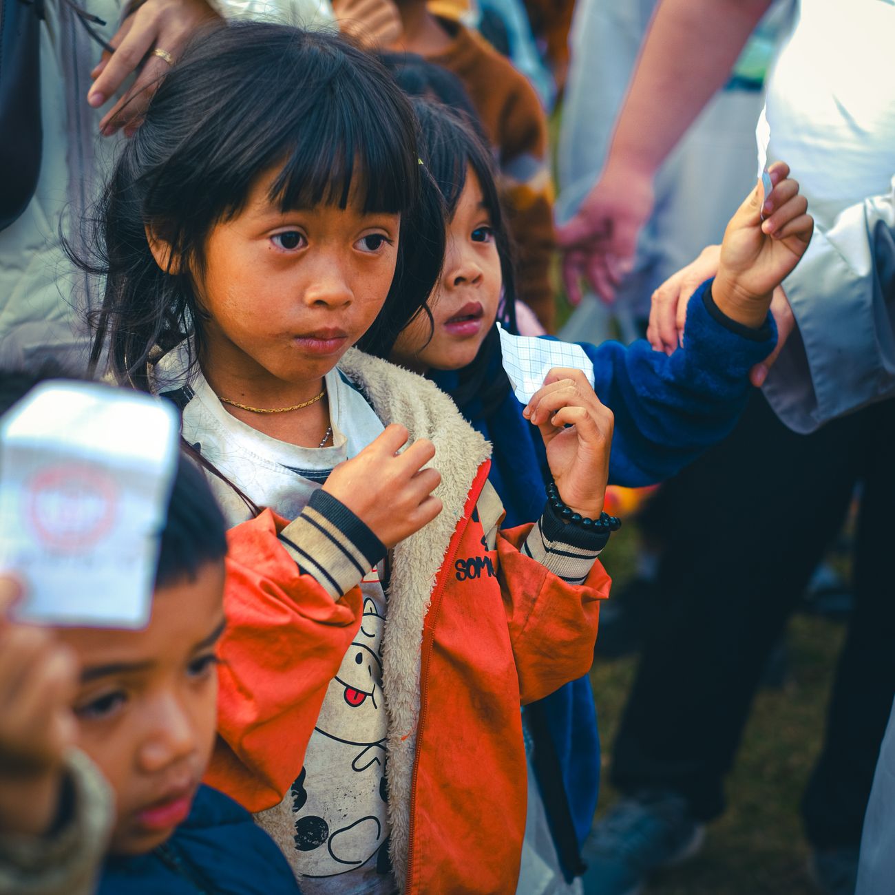 A group of children holding tickets outdoors, curious and excited