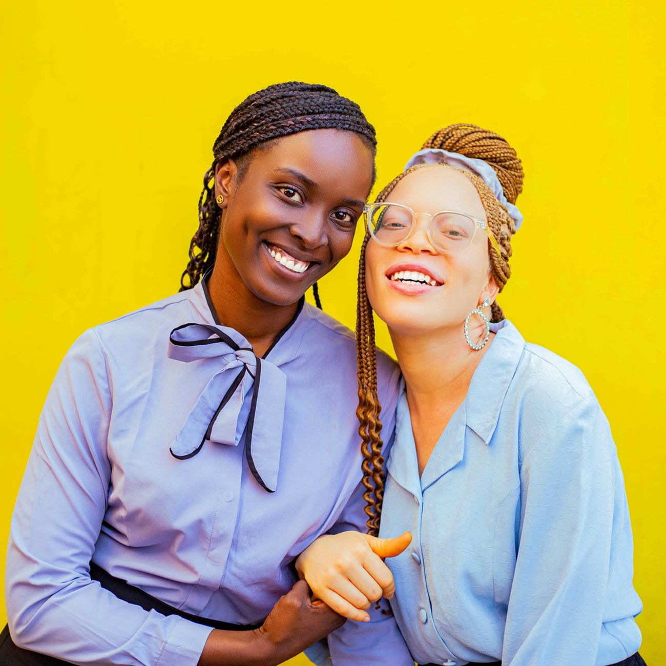 Two friends smiling against a yellow background