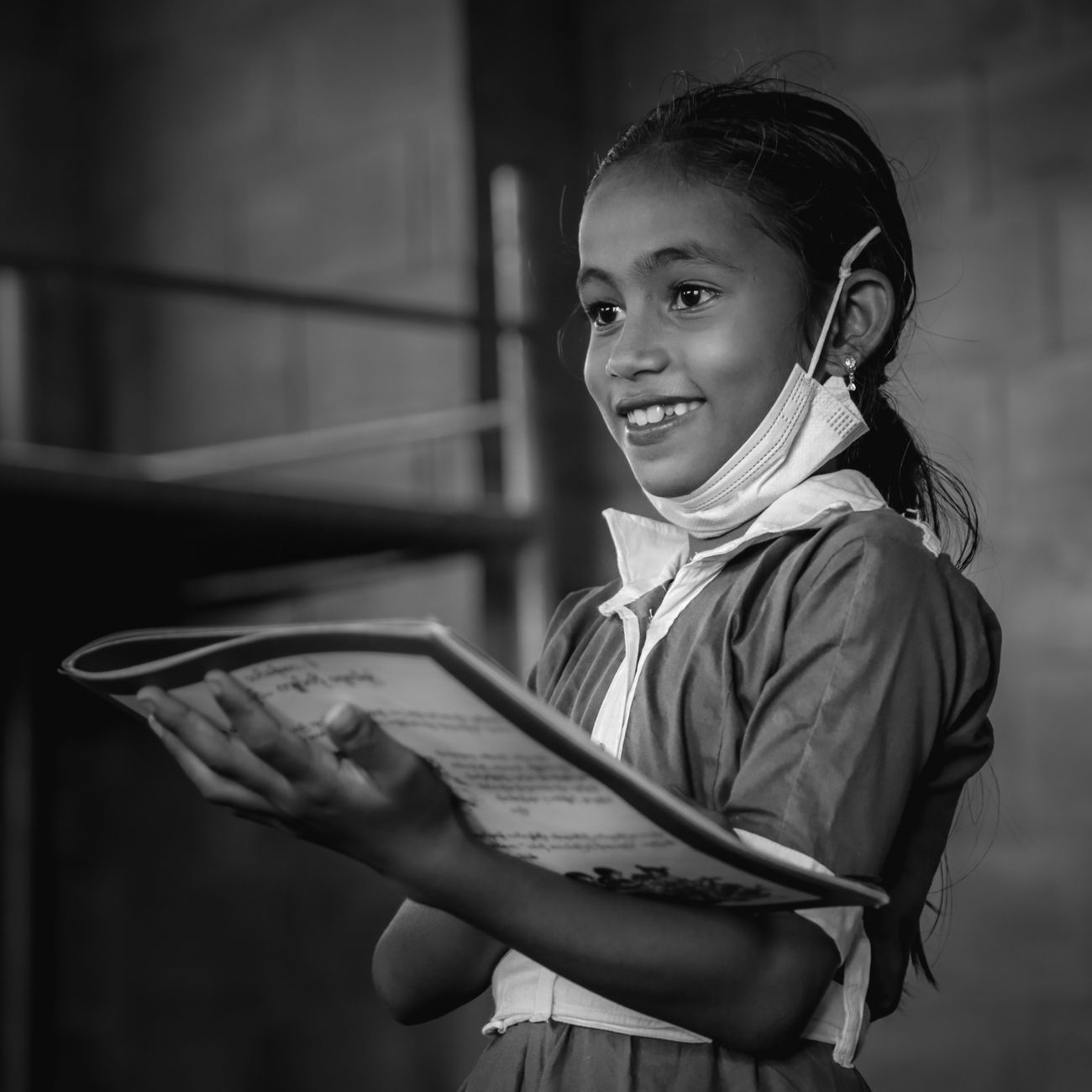 A joyful young girl reading a book, captured in a black and white photograph.