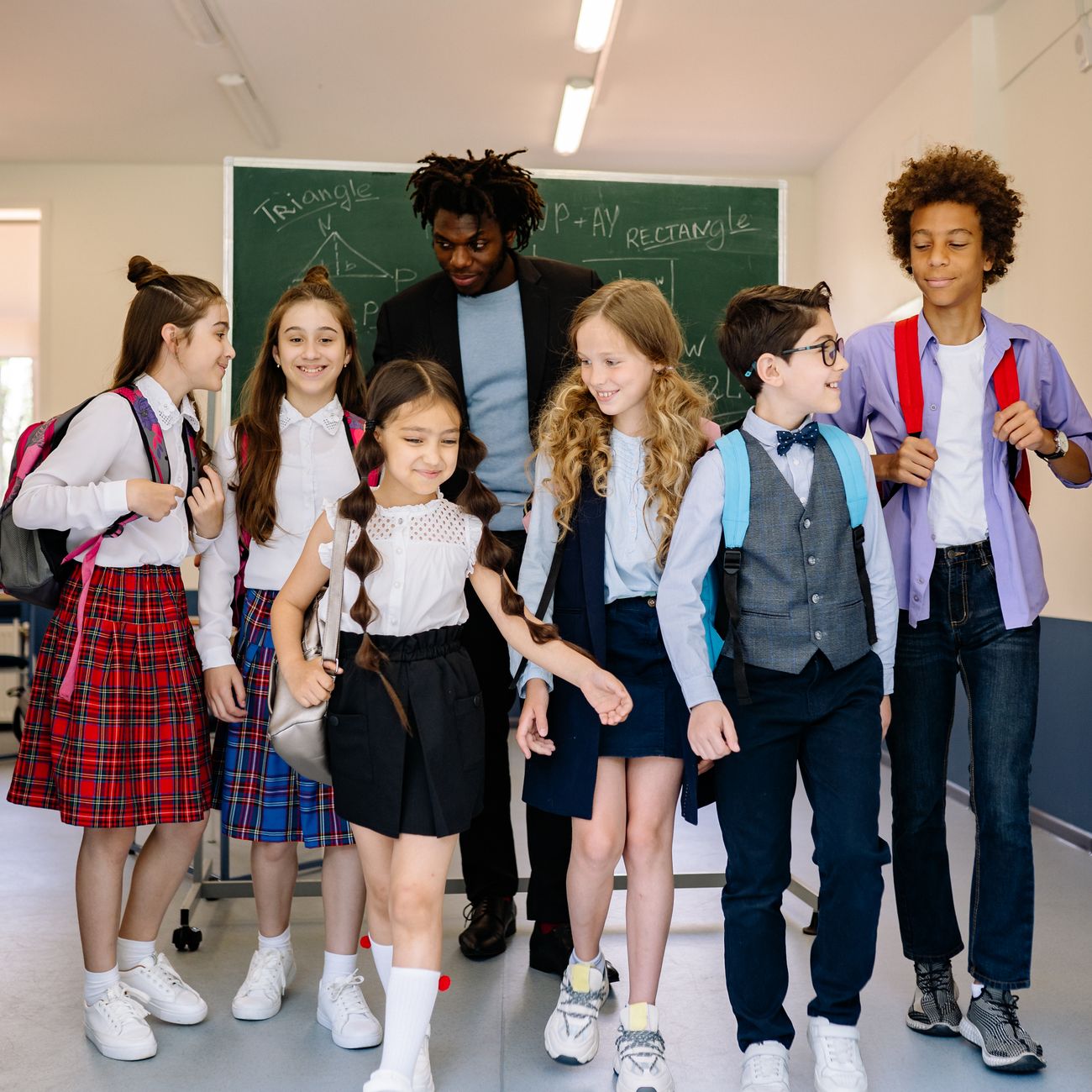 Group of schoolchildren with their teacher walking together inside a classroom