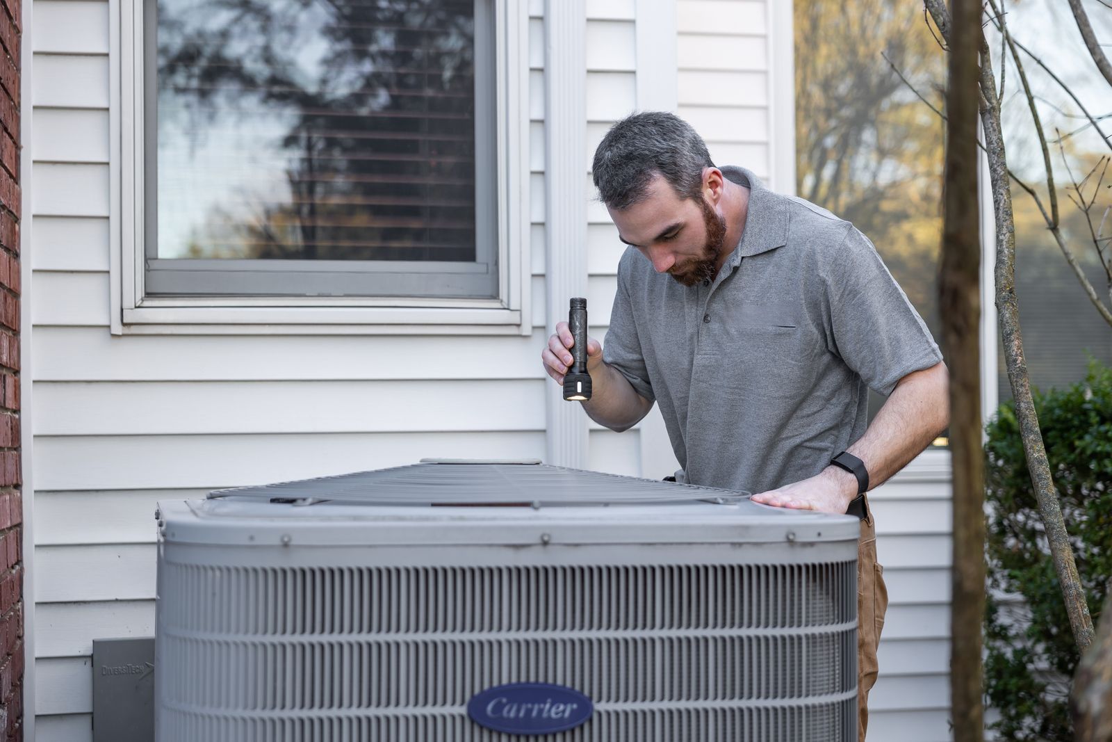 Technician inspecting an outdoor air conditioning condenser