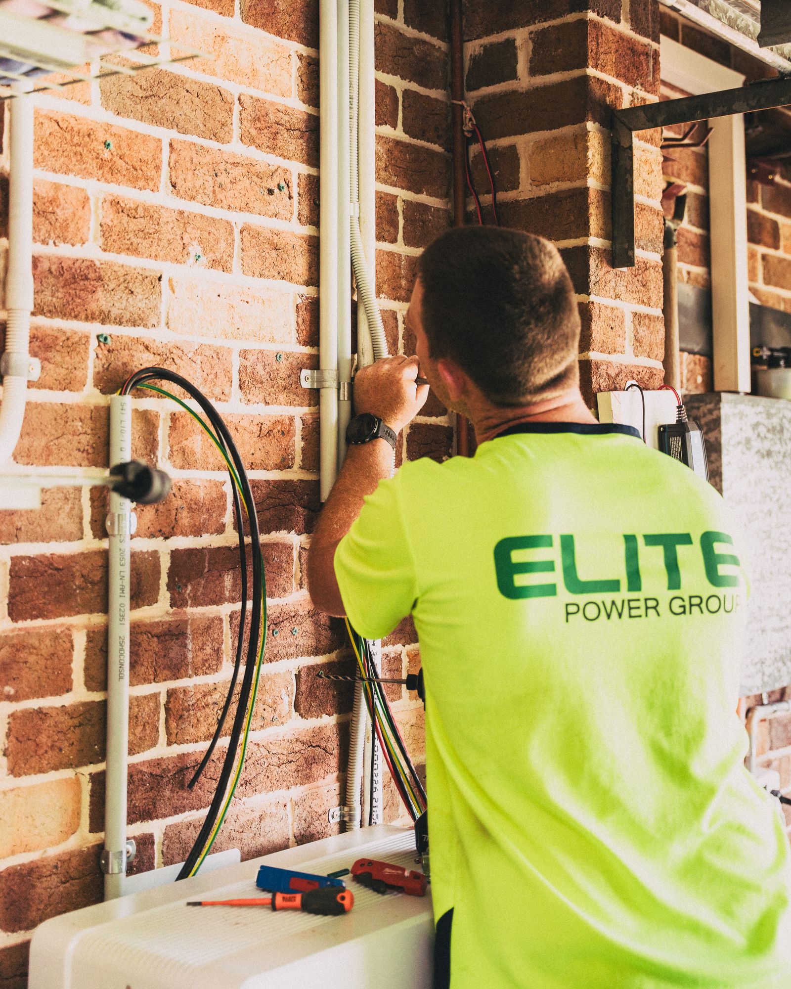 Electrician connecting conduit and cabling on a brick wall