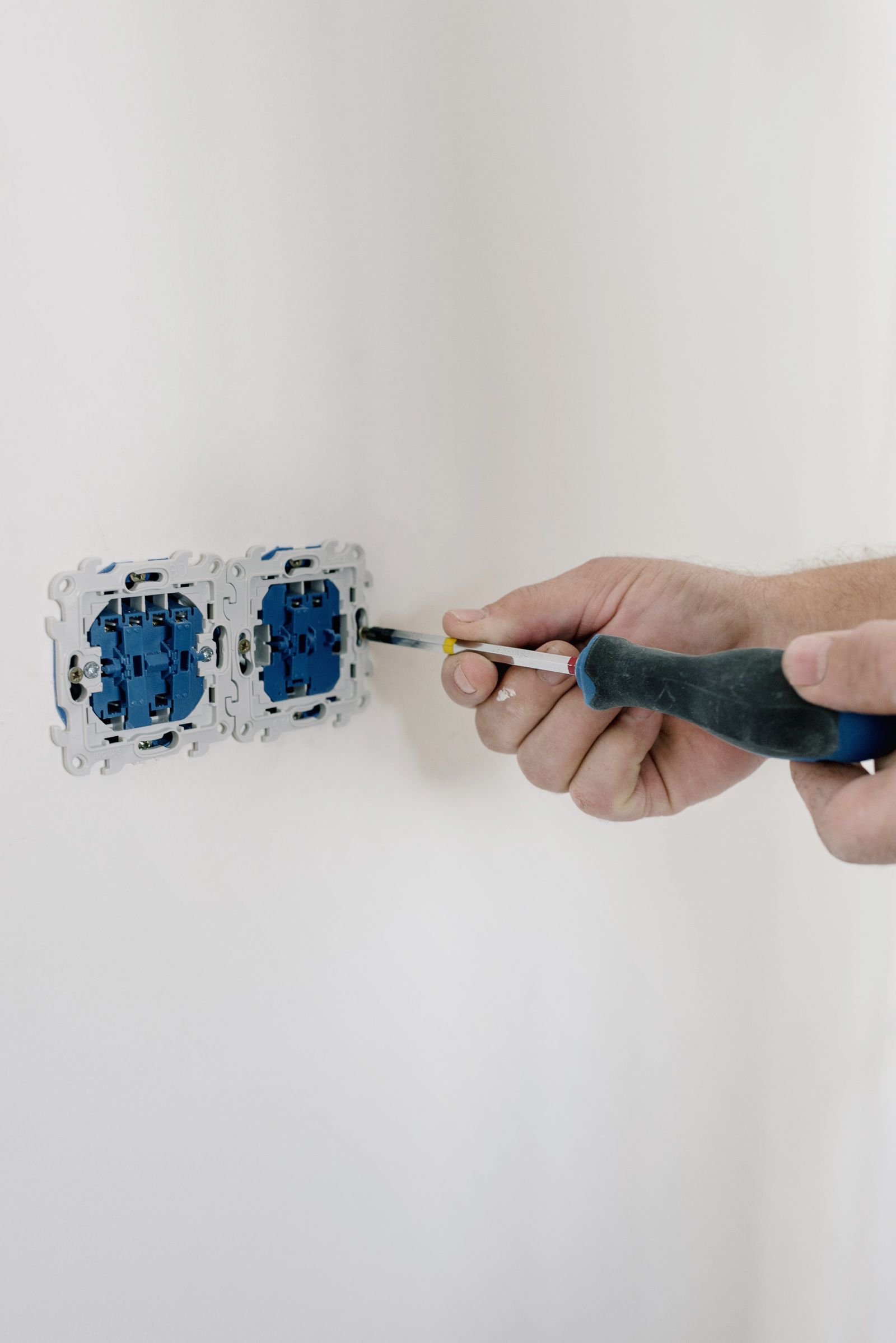 Hands installing a double electrical wall outlet